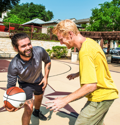 Two young men playing basketball outside